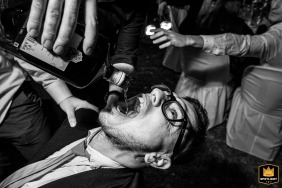 In a black and white shot at the Santa Fe Hotel, the groom's friends are seen giving him a drink of scotch whiskey during the wedding festivities.